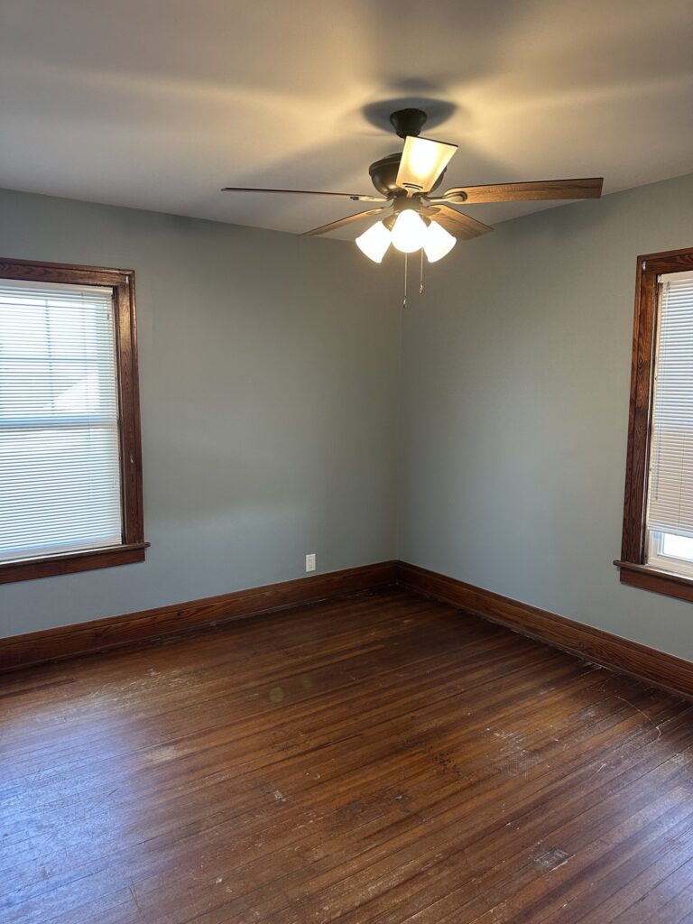Bedroom with hardwood floors and two windows