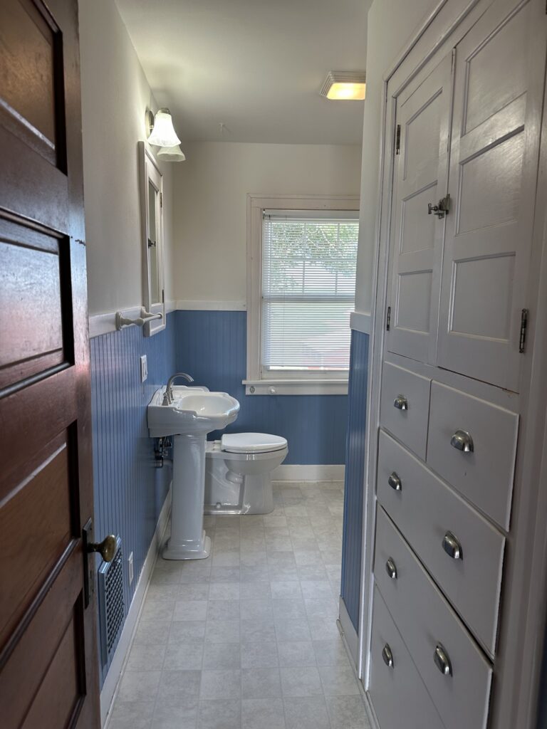 Full bathroom with pedestal sink and built-in linen storage